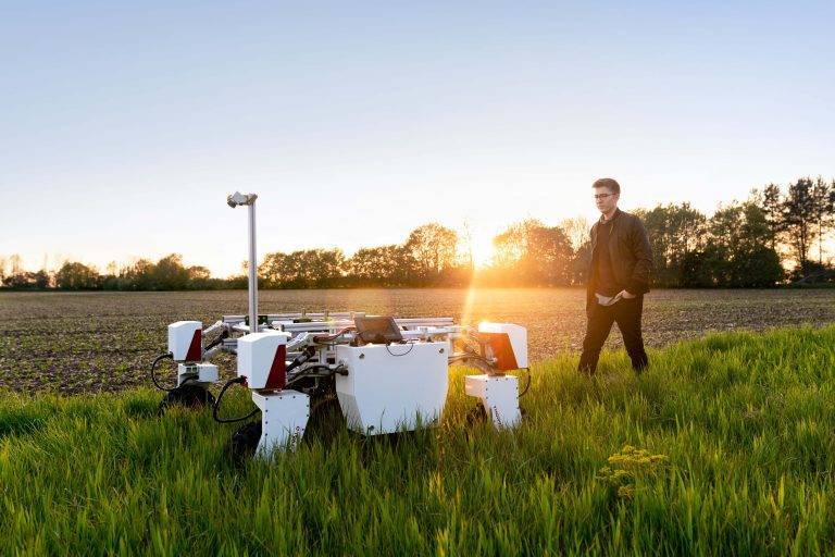 Man walking on a field with a robot