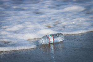 Botella de plástico tirada en la orilla junto a la nieve en invierno
